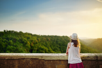Young girl enjoying sunset view in the famous Pitigliano town, located atop a volcanic tufa ridge. Beautiful italian towns and villages. Etruscan heritage, Grosseto, Italy.