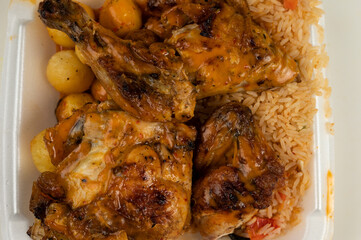 Portuguese Peri Peri Chicken on top of rice and potato balls  in a styrofoam dish 