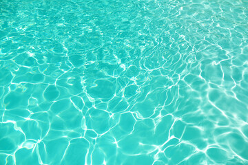 Ripples in the water in swimming pool with sun reflection.