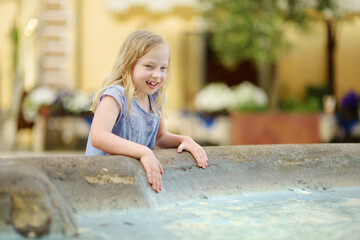 Young girl playing in a fountain of Pitigliano town, located atop a volcanic tufa ridge. Beautiful italian towns and villages. Etruscan heritage, Tuscany, Italy.