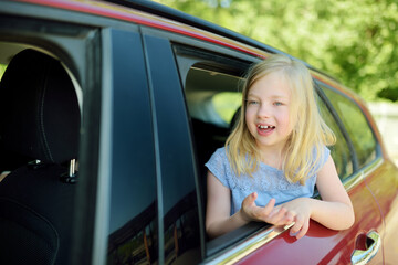 Funny young girl sticking her head out the car window looking forward for a roadtrip or travel.