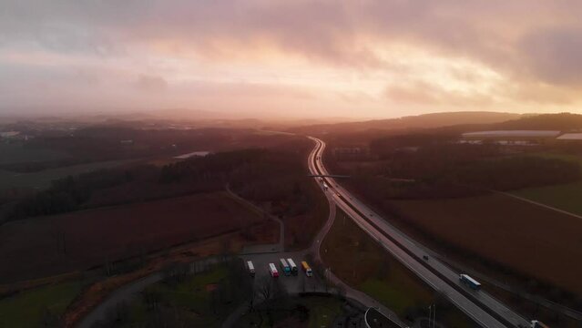 Aerial shot over European route E6 with traffic in Sweden during mystic golden sunset at horizon