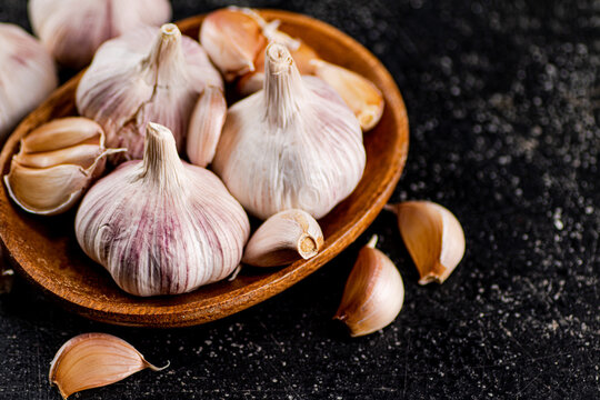 Fresh garlic on a wooden plate. On a black background. High quality photo