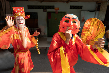Men wear masks and red robes and perform in the street during traditional celebration of lunar new year or Tet in Vietnam.