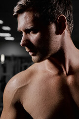 Muscular athletic bodybuilder fitness model posing after exercises in gym close up