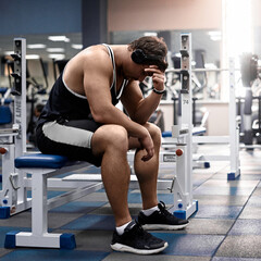 Muscular athletic young man fitness model sitting tired after exercises in gym black and white