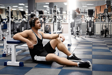 Muscular athletic bodybuilder fitness model posing after exercises in gym