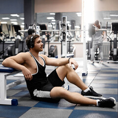 Muscular athletic bodybuilder fitness model posing after exercises in gym