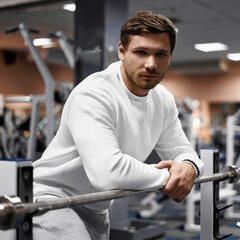 Portrait of handsome young muscular caucasian man posing in gym, Confident fitness trainer in modern sport club interior advertising healthy lifestyle