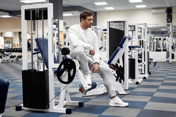 Portrait of handsome young muscular caucasian man posing in gym, Confident fitness trainer in modern sport club interior advertising healthy lifestyle