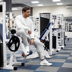 Portrait of handsome young muscular caucasian man posing in gym, Confident fitness trainer in modern sport club interior advertising healthy lifestyle