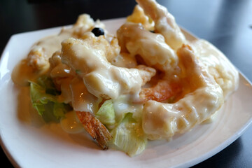 It's a fried shrimp with cream sauce on a white plate.