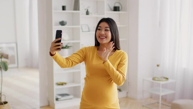 Online Communication. Pregnant Asian Woman Making Video Call With Smartphone At Home