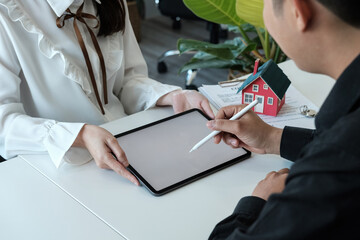 Real estate brokers point to a contract and advise customers to sign name digital tablet customer...