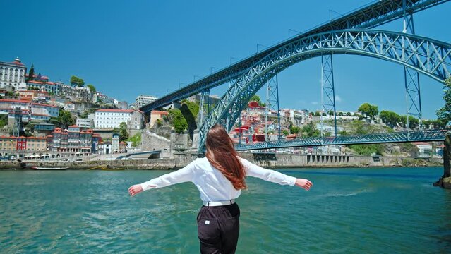 A tourist girl walking by the Ponte Lu&iacute;s I Bridge in Porto enjoying the culture. A fashionable woman walking in slow motion and exploring the city center of Porto in Portugal, Europe.