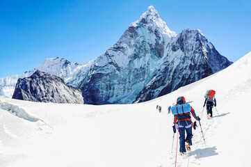 Fototapeta na wymiar Group of equipped mountaineers crossing snowfield on a way to summit. On a background view on Mount Ama Dablam in Nepal
