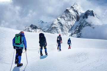 Group of climbers with backpacks and tied with rope crossing Khumbu glacier crevasse during ascent on Everest