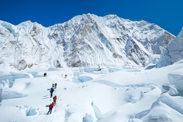 Group of climbers crossing Khumbu glacier crevasses reaching the Everest summit in Nepal. Team work concept.