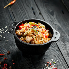 Chicken fried rice on wok. Asian food - fried rice with vegetables, egg and chicken on dark table. Wok menu on black wood background. Traditional chinese food.