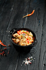 Chicken fried rice on wok. Asian food - fried rice with vegetables, egg and chicken on dark table. Wok menu on black wood background. Traditional chinese food.