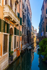Fototapeta na wymiar Traditional Venice cityscape with narrow canal, moored boats and ancients colorful buildings on banks of canal, Italy