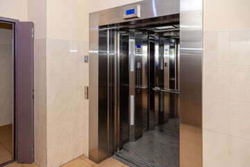 The elevator entrance is in modern office with marble wall. Lift transportation floor to floors with push switch for up and down.