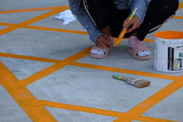 Workers are painting diagonal lines, not stopping the car in front of the building.