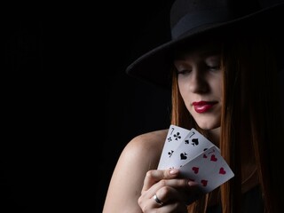 a girl in a hat with playing cards three sevens on a black isolate