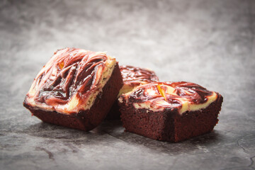 Three pieces of Red velvet brownie cheese cake on dark marble background.