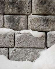 wintertime square and rectangular-shaped blocks stacked for strength of retaining wall of outdoor building in winter vertical format background 