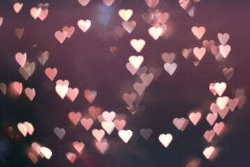 Abstract blur with pink and red bokeh hearts on a black backdrop for a wedding card or Valentines day
