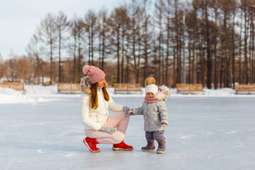 young smiling girl and a two-year-old girl walk in the park in winter
