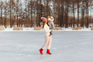 beautiful slender woman lifts a two-year-old girl. people in winter in outerwear