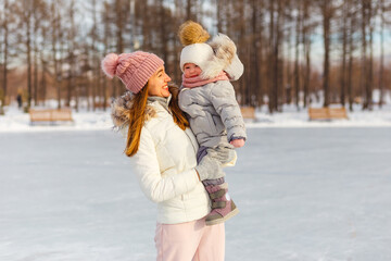 beautiful slender woman lifts a two-year-old girl. people in winter in outerwear