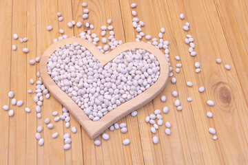 Close up shot of white beans raw in a heart-shaped plate