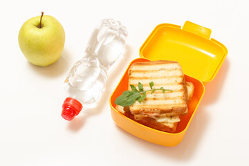 Yellow lunch box with toasted slices of bread, cheese and green parsley.