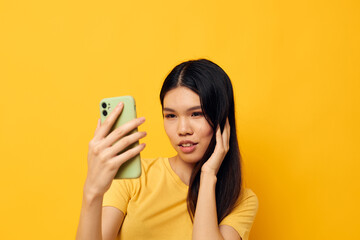 pretty brunette in a yellow t-shirt looking at the phone posing isolated background unaltered