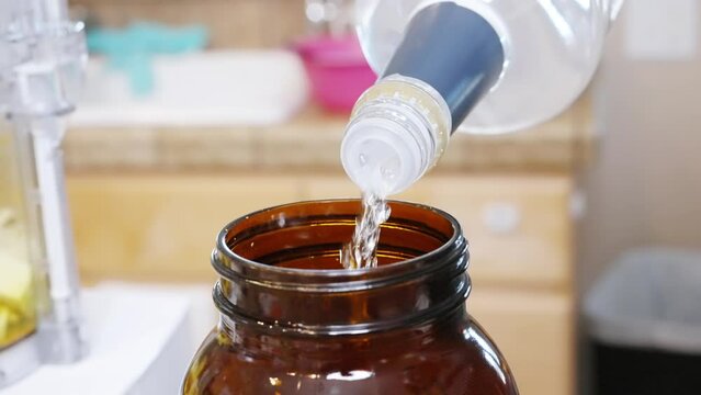 Pouring pure alcohol into a blend of turmeric, peppers, horseradish and garlic to make a homemade tincture - side view