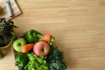 Fresh organic vegetables and fruits  in a basket on wooden background.
