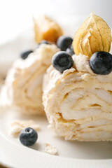 Two pieces of meringue roll with berries on a plate.