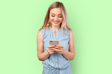 Portrait of a smiling casual woman holding smartphone over color background