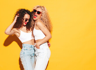 Two beautiful sexy smiling hipster women in summer clothes. Trendy models with afro curls hairstyle...