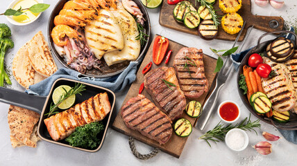 Grilled fish, seafood and meat assortment on light background.