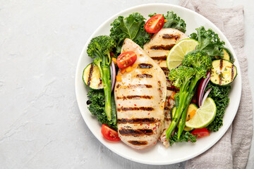 Grilled chicken with vegetables on light background.