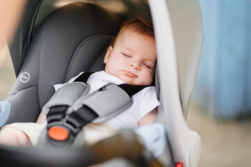 a little boy sleeps strapped in a stroller. 