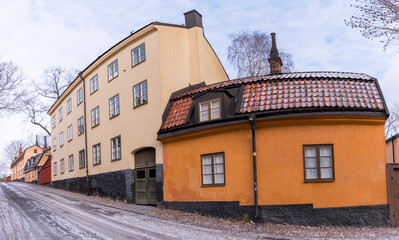 Old yellow houses from the 1700s with black tin roofs, chimneys and roof dorms a cold sunny winter day in Stockholm