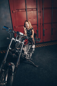 stylish girl on a motorcycle in a leather dress on the background of a virtual reality garage
