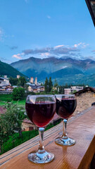 Two glasses of Georgian red wine and panoramic view on the Svan towers in Mestia, a highland...
