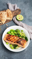 Baked salmon with vegetables on dark background.