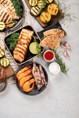 Grilled fish, seafood and meat assortment on light background.